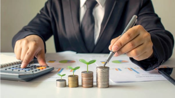 Person calculating and placing coins with small plants growing from stacks, symbolizing controlled financial growth